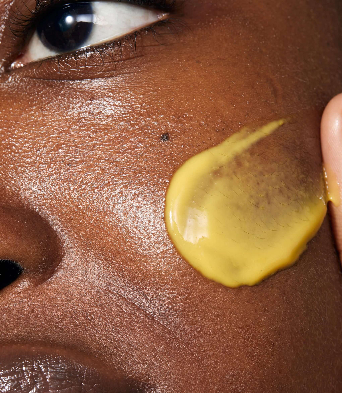 Model applying Midnight Renewal Serum to her face. The product has a light texture and a yellow colour.