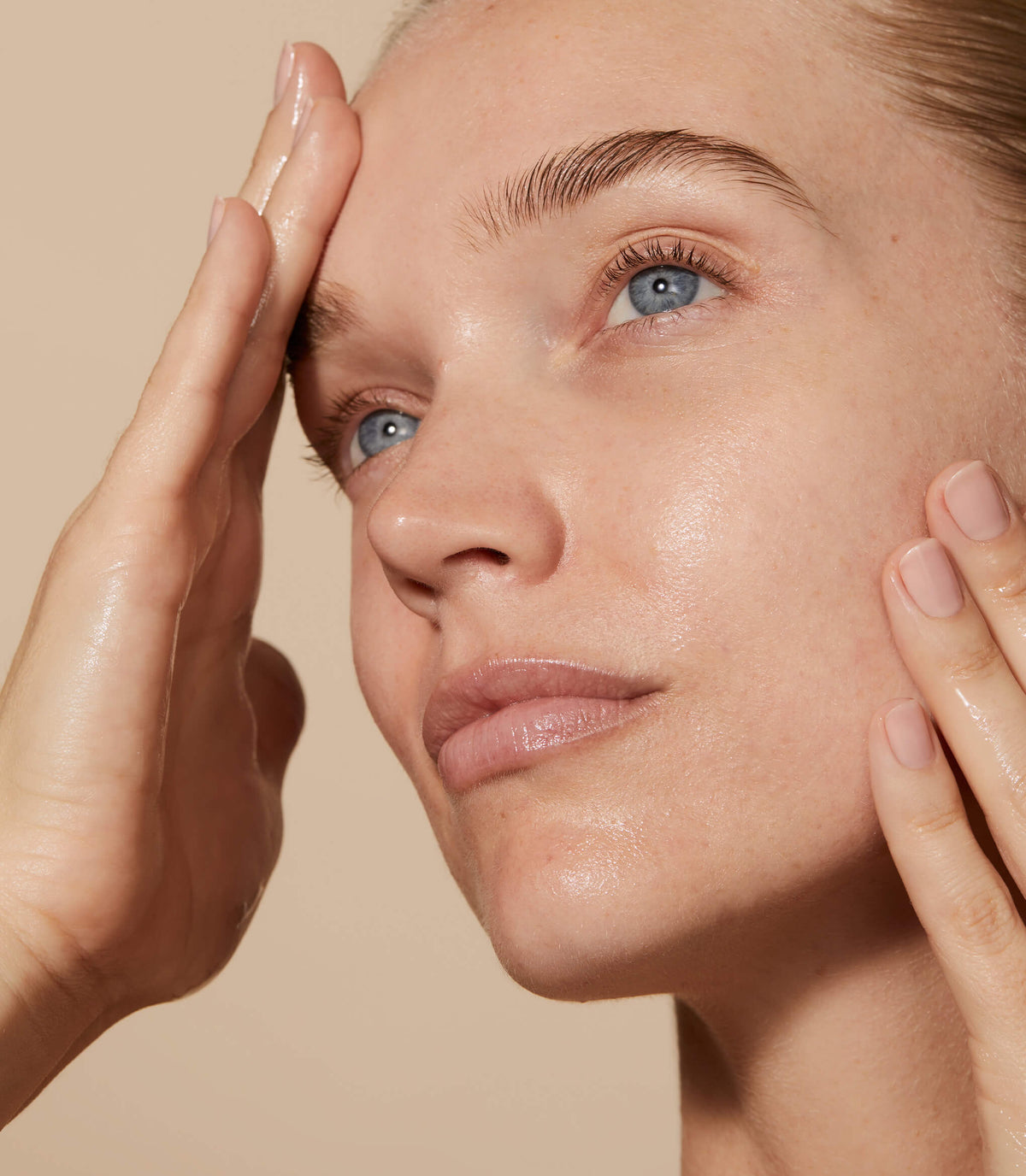 A close up of model's face with Omoressence applied to her skin.