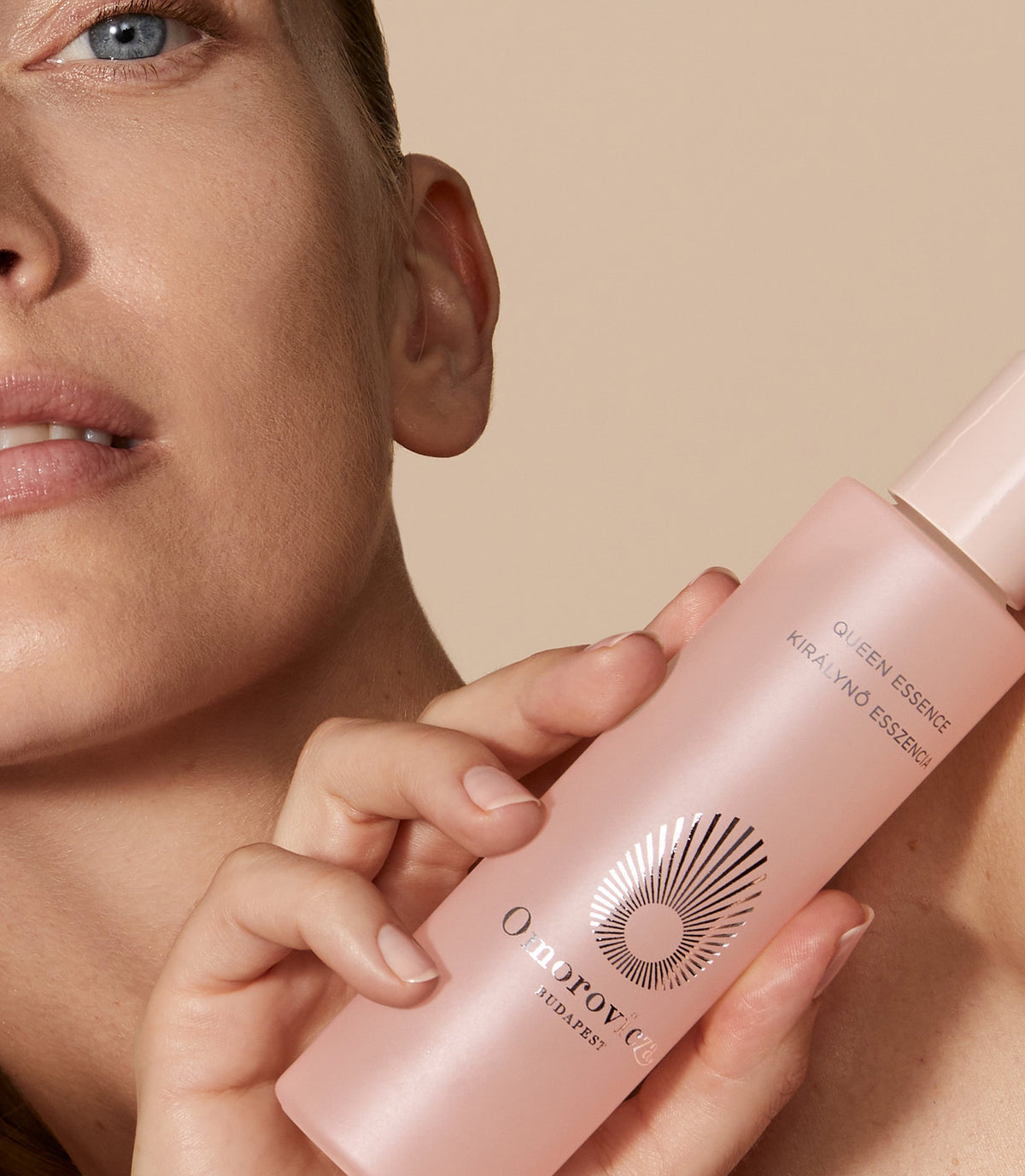 Model holding a bottle of Queen Essence close to her shoulder 