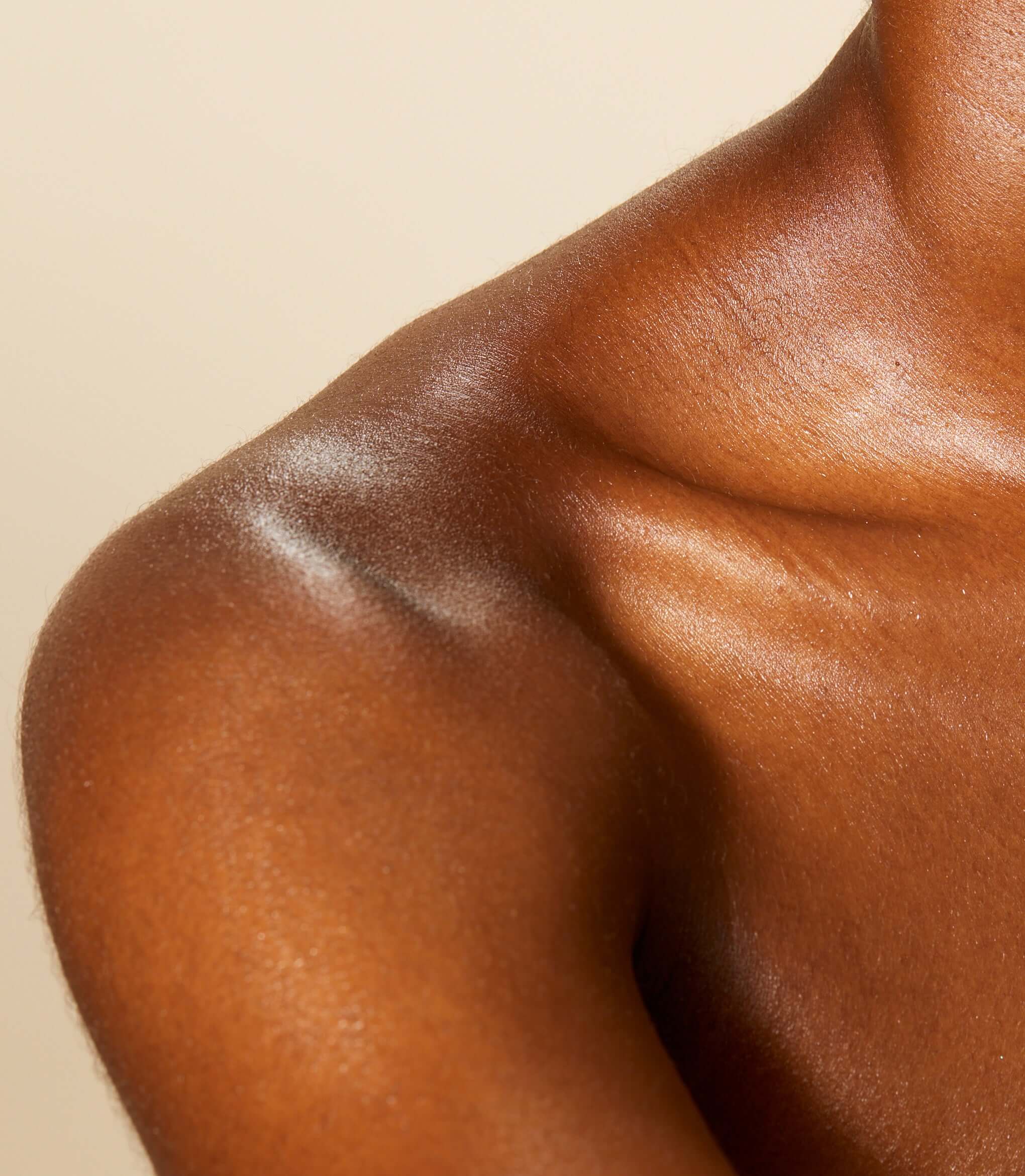 A close up of model's neck and collarbone with Firming Neck Cream applied to her skin.