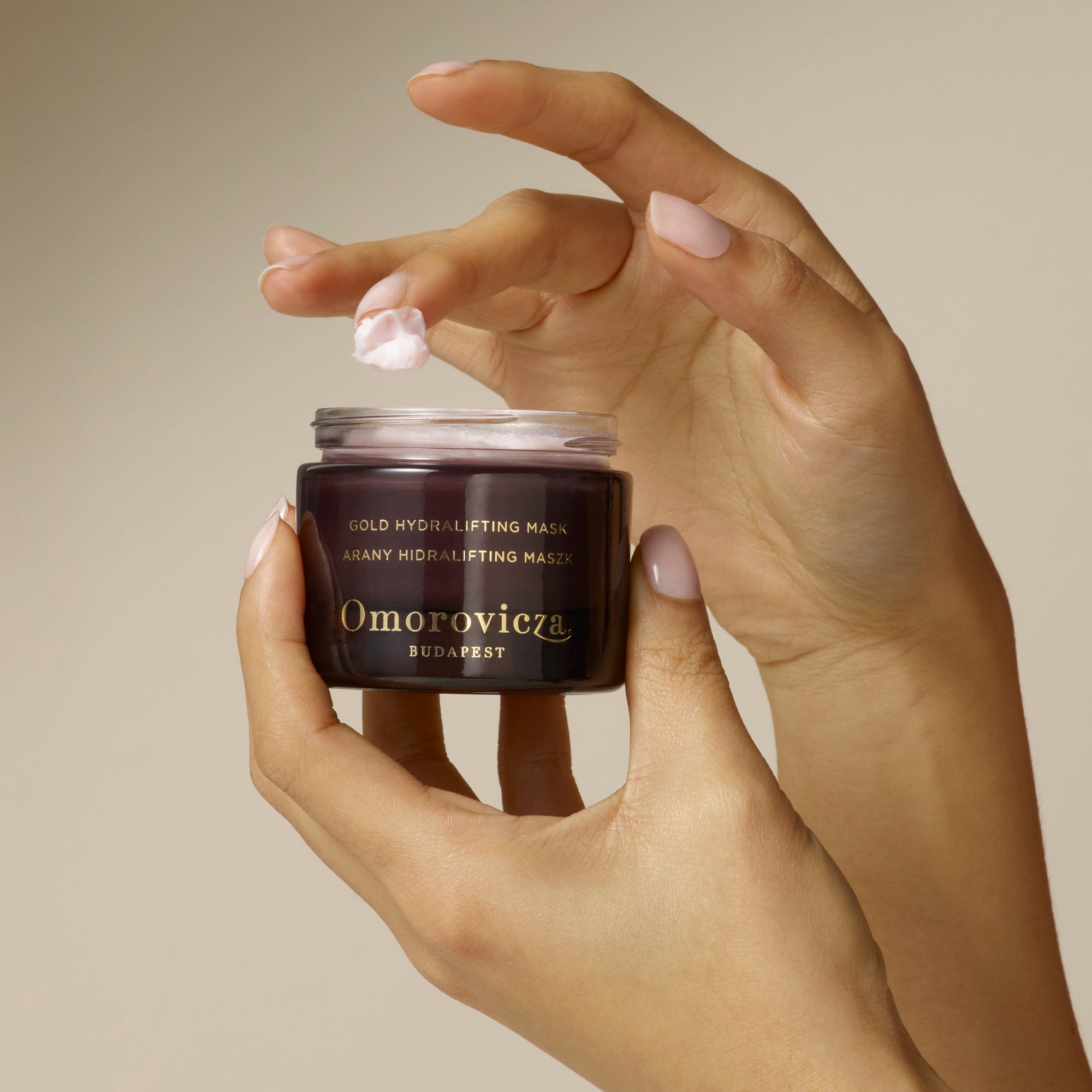 hands are holding Gold Hydralifting Mask with a little bit of products on their finger.