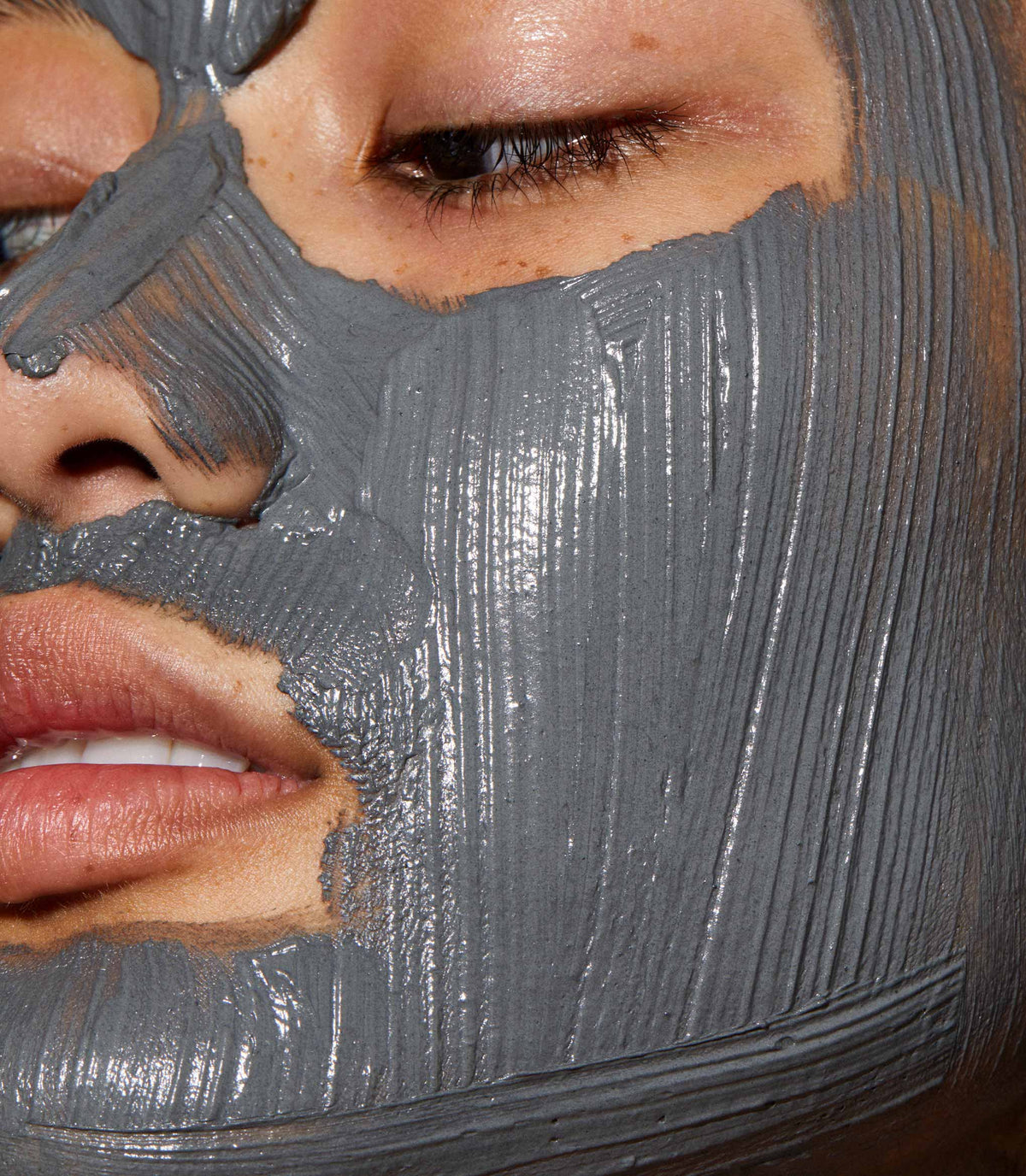A close up of models face with Ultramoor Mud Mask applied to her face.